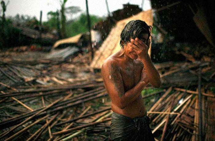 13. Hhaing The Yu, 29, holds his face in his hand as rain falls on the decimated remains of his home near Myanmar’s capital of Yangon (Rangoon). In May 2008, cyclone Nargis struck southern Myanmar, leaving millions homeless and claiming more than 100,000 lives