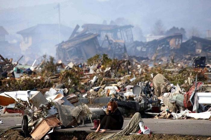 8. A woman sits amidst the wreckage caused by a massive earthquake and ensuing tsunam, in Natori, northern Japan, in March 2011