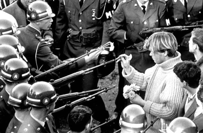 9. Protestors place flowers into the rifle barrels of armed officers